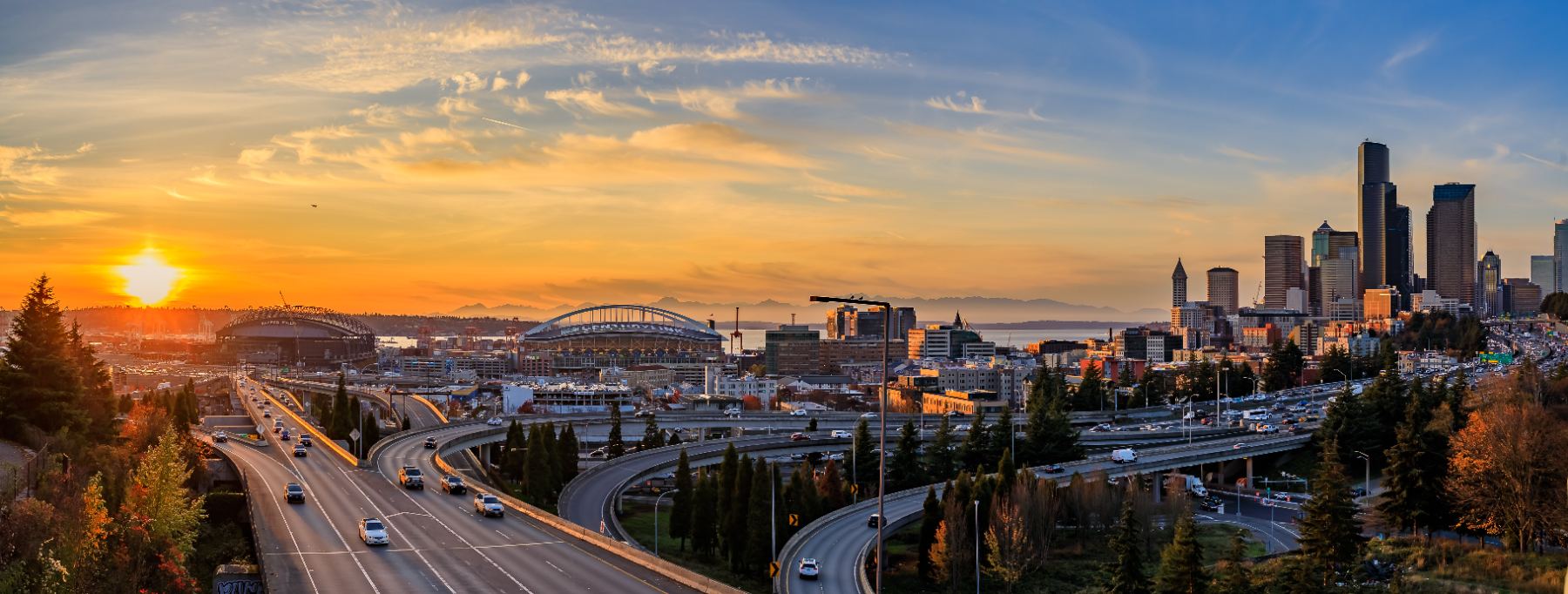 Seattle skyline at sunset with highways, Puget Sound, and Mount Rainier in distance