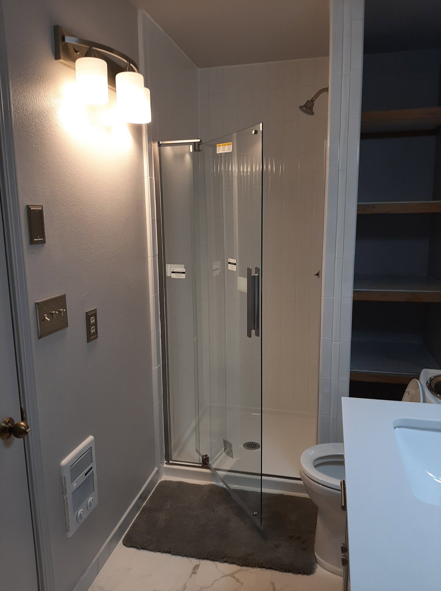 Modern bathroom with glass shower enclosure, toilet, and vanity lighting