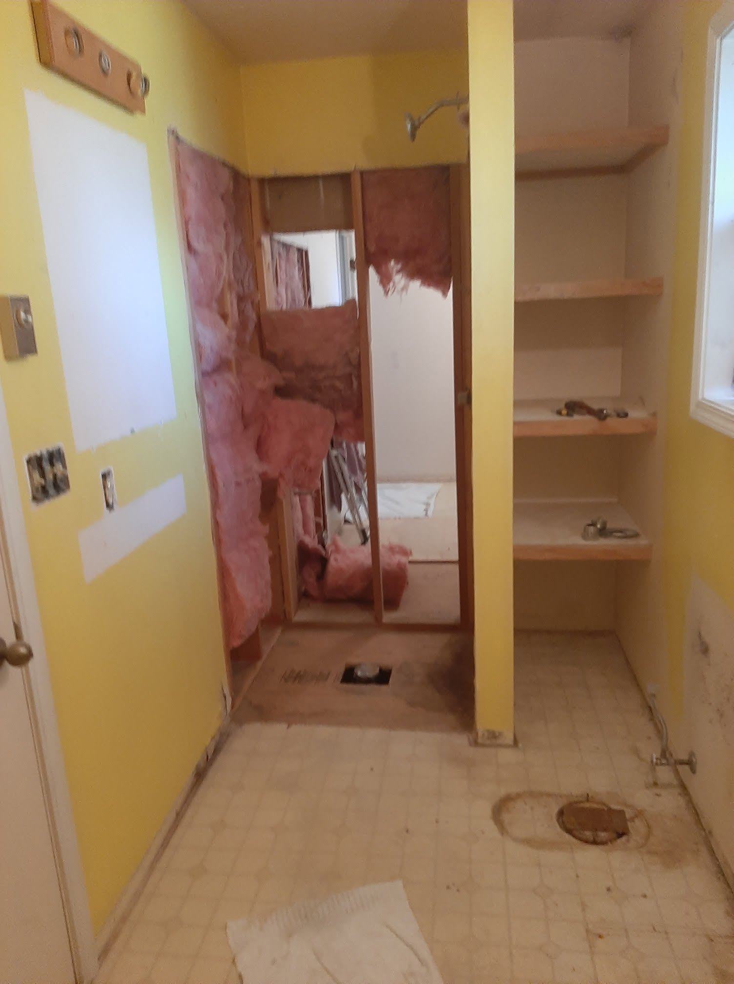 Yellow bathroom under renovation with red tile walls and exposed plumbing fixtures