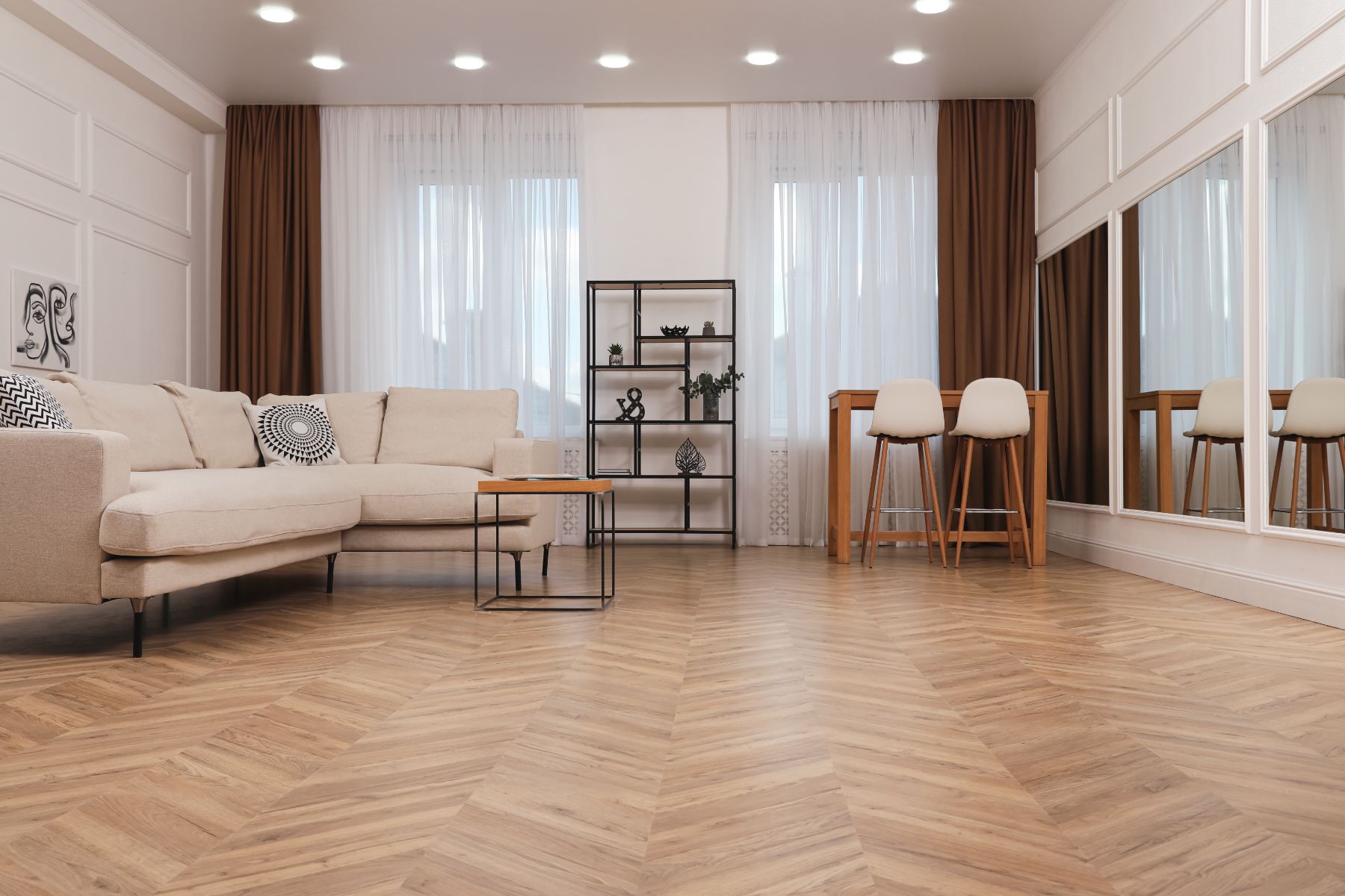 Modern living room with beige sofa, wooden dining table, bar stools, and herringbone flooring