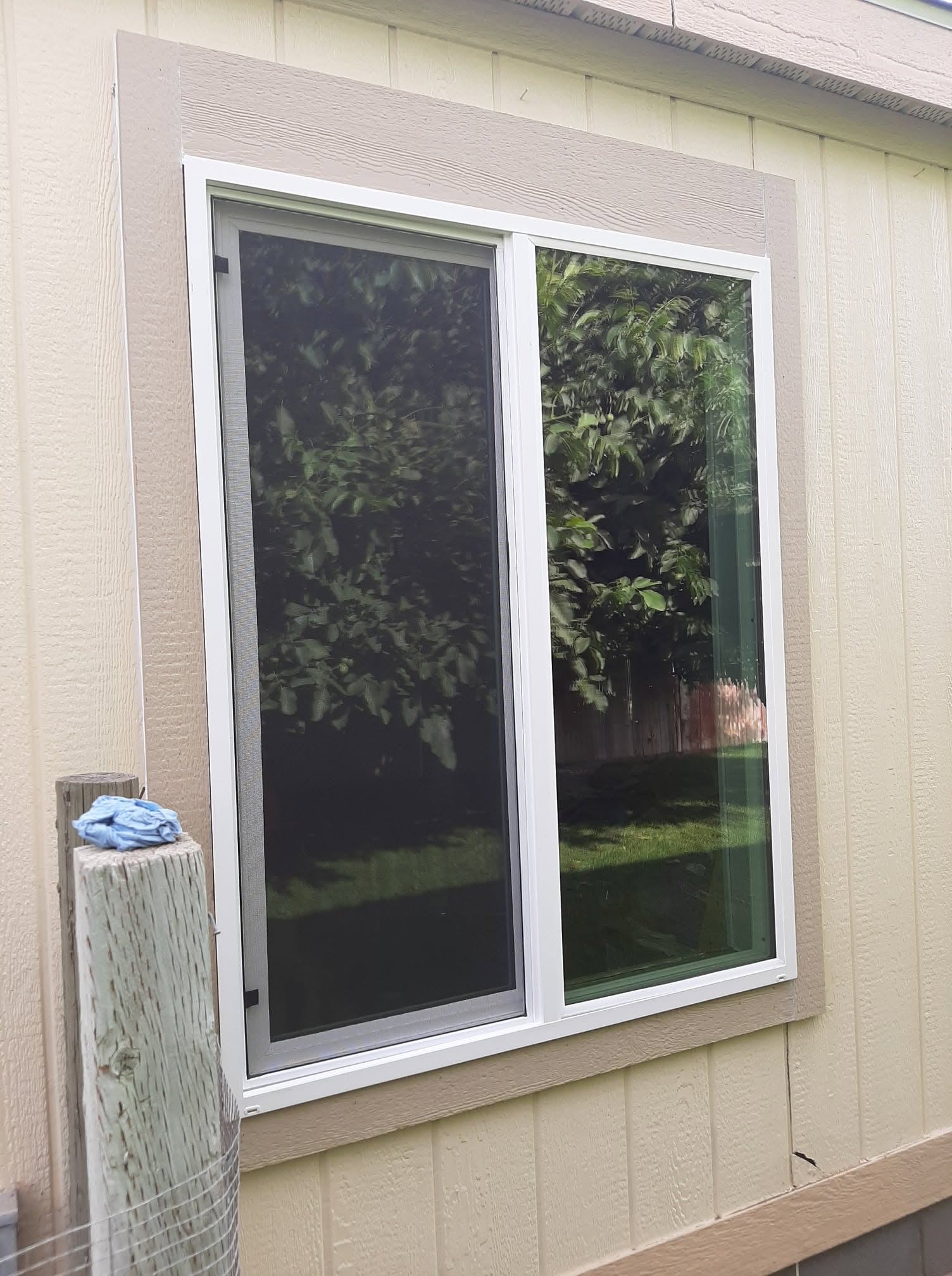 White-framed sliding glass doors with screens installed on cream-colored siding exterior wall